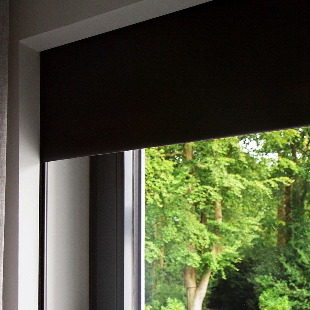 Blackout roller shade lowered from a recessed ceiling pocket with hidden side channels
