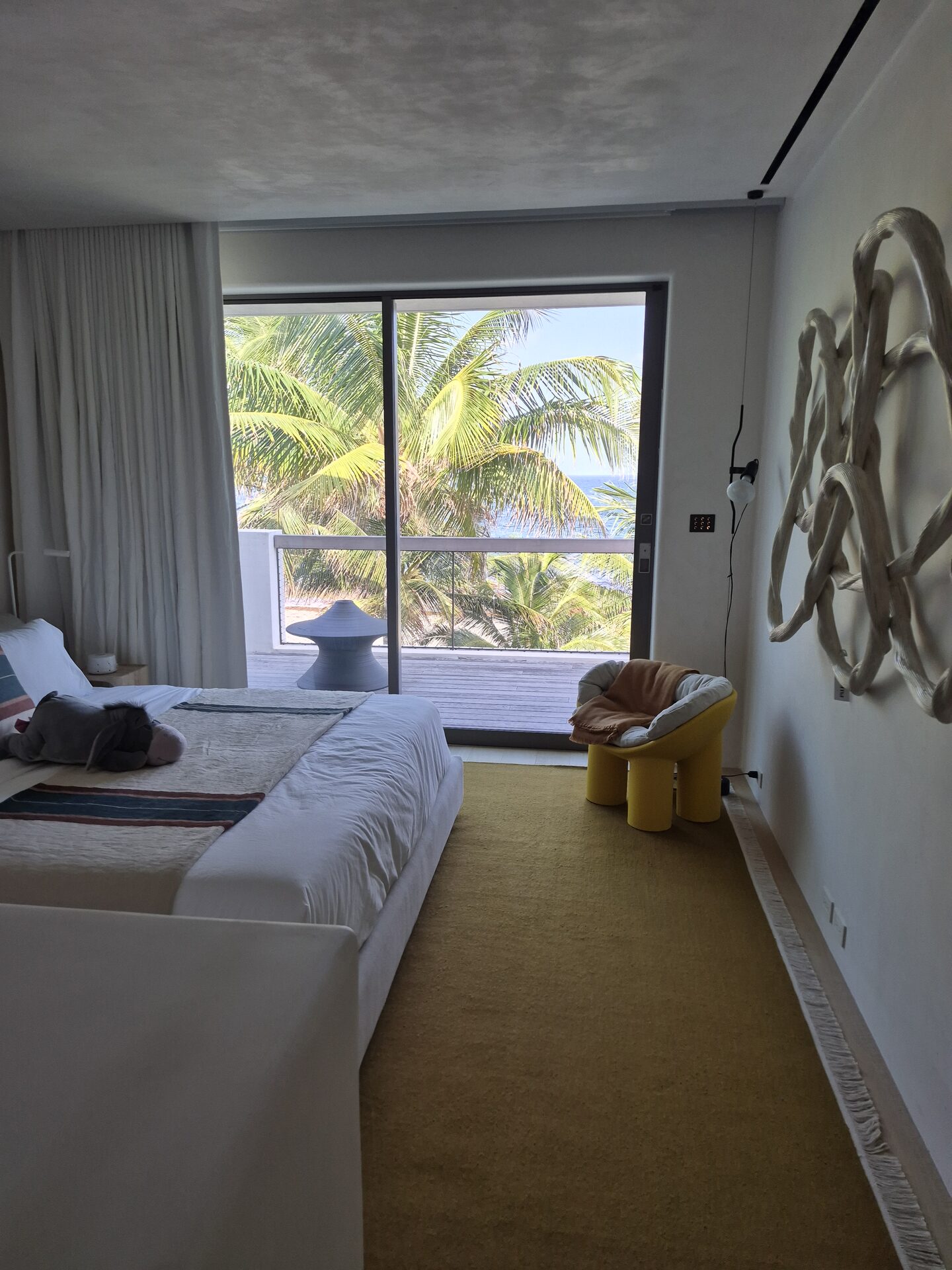 Sheer draperies diffusing light in an oceanfront bedroom with palm views