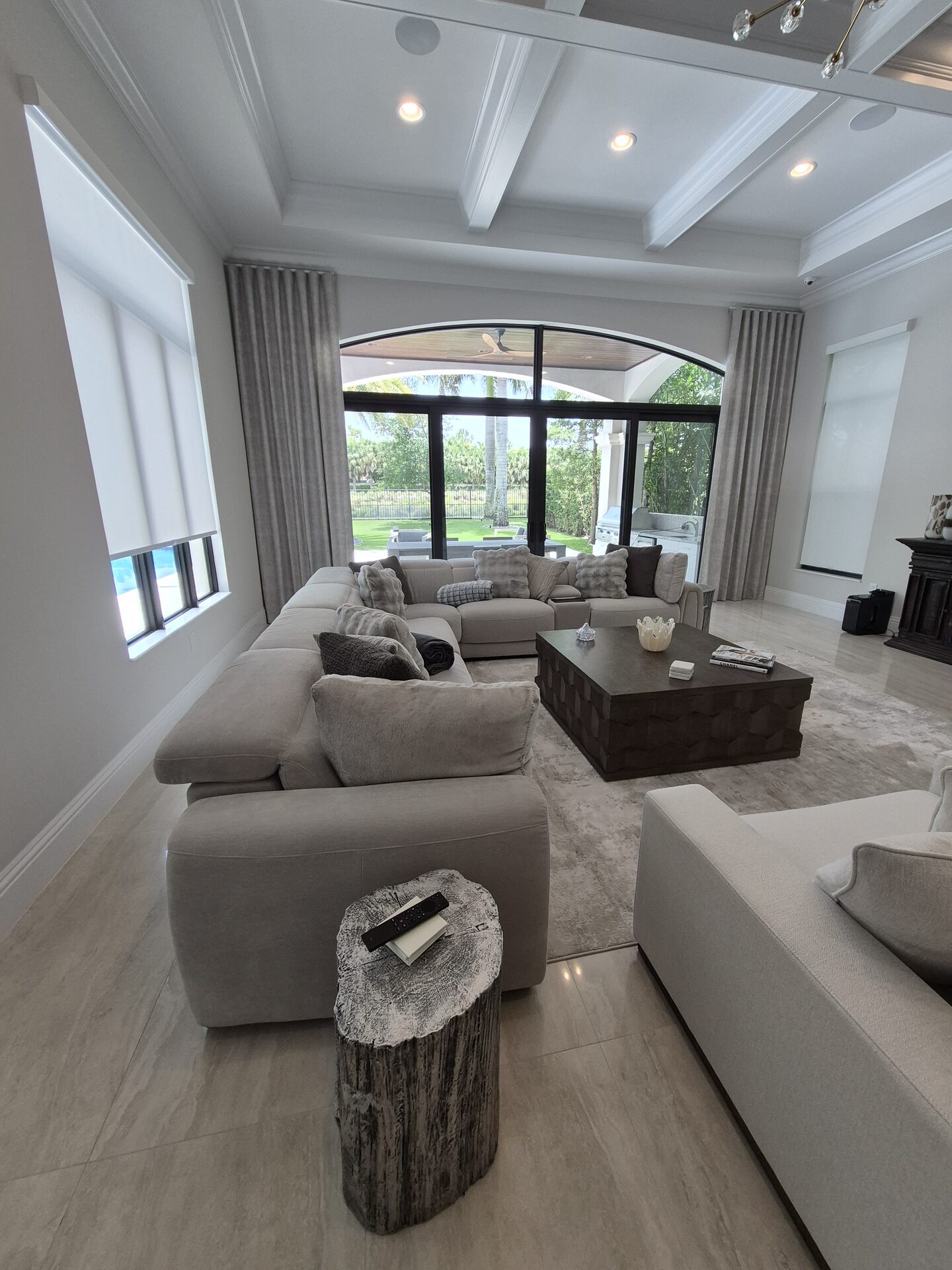 Roller shades and draperies on an arched sliding door opening to a pool terrace