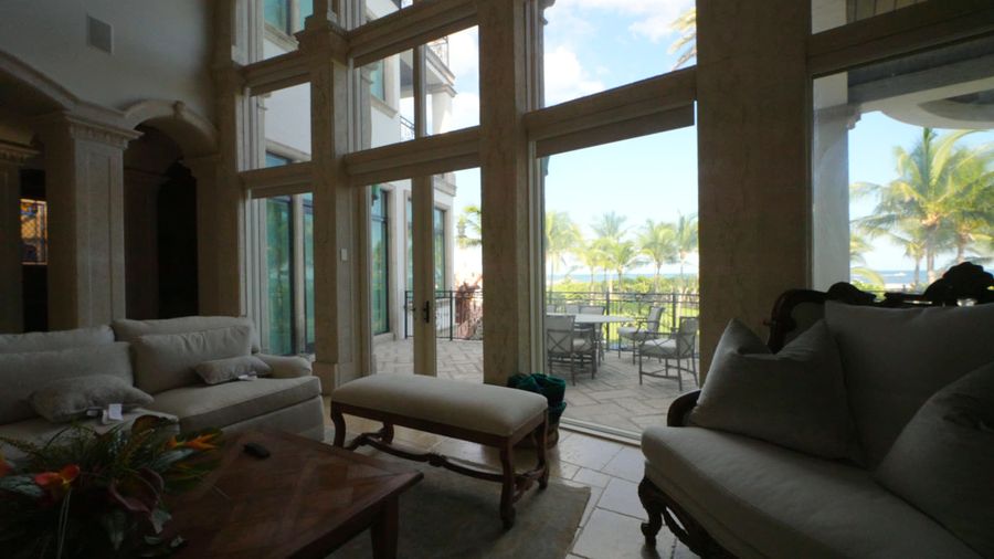 Arched window wall with motorized blackout roller shades raised, terrace, palms and ocean beyond, Pompano Beach