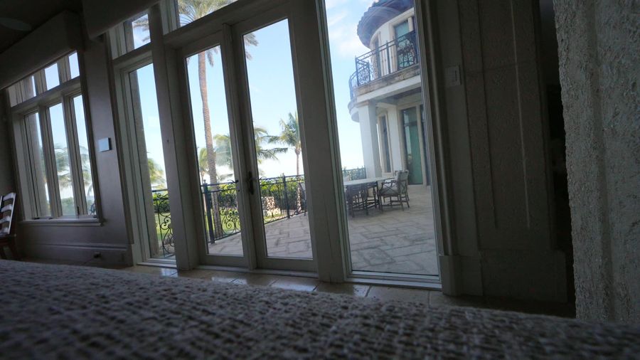Tall French doors to a terrace with a motorized blackout shade raised, Pompano Beach