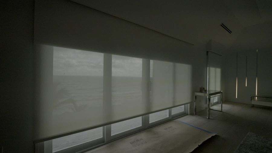 Luna White Lutron blackout shade rolling up off a wall of ocean glass, Hillsboro Beach