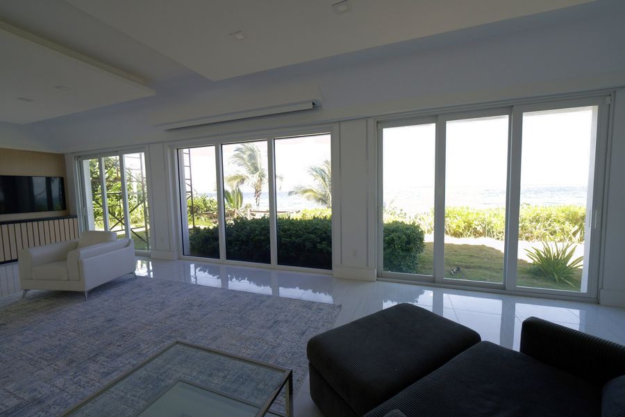 Motorized Lutron shades across the oceanfront living room glass of a Hillsboro Mile mansion