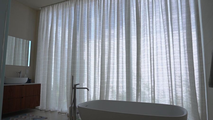 Primary bathroom with a freestanding tub against floor-to-ceiling sheer draperies, Miami Beach