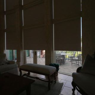 Phifer SheerWeave 7700R Sand blackout roller shades halfway down on an arched window wall, Pompano Beach