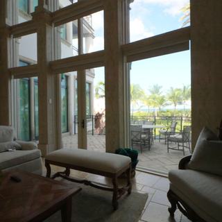 Arched window wall with motorized blackout roller shades raised, terrace, palms and ocean beyond, Pompano Beach