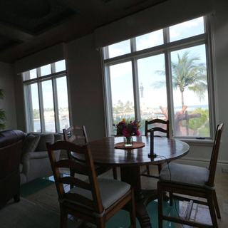 Breakfast nook with a round table and motorized blackout shades raised on the windows, palms outside, Pompano Beach