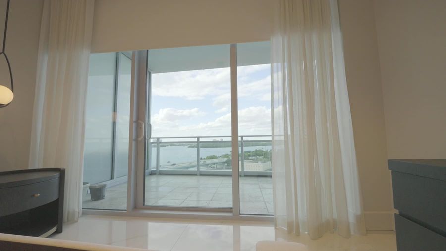 Bedroom sheer draperies at an open slider with the bay beyond, Sunny Isles Beach