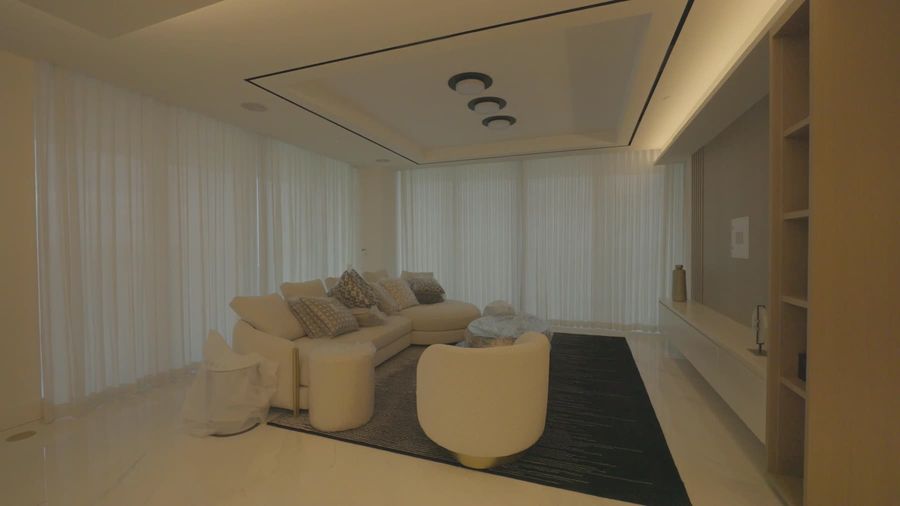 Living room with wood built-in, cove lighting and motorized sheer draperies in Sunny Isles Beach