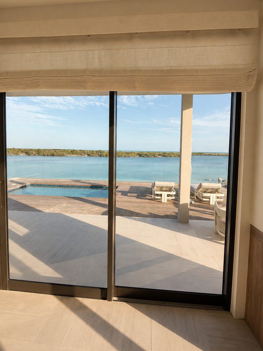 Lutron blackout shade on a floor-to-ceiling slider with pool view, Turks and Caicos