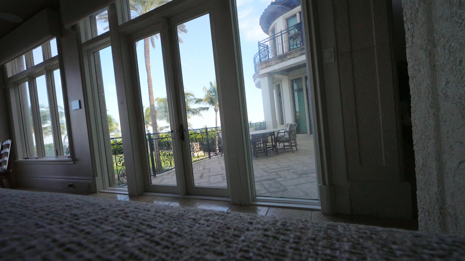 Tall French doors to the terrace with the motorized shade raised, the house next door beyond