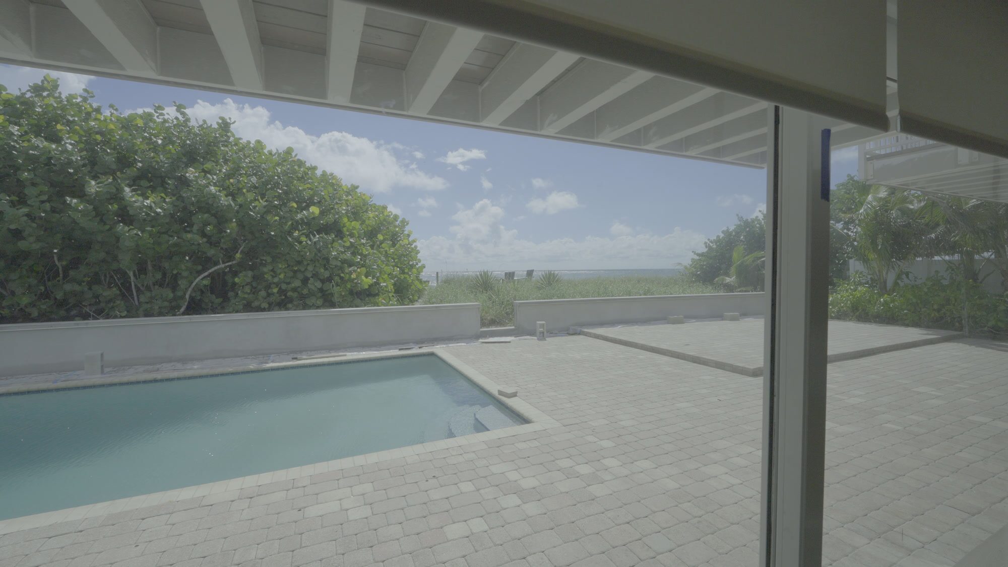 Sliding glass door open onto the pool deck, sea grapes and the Atlantic beyond