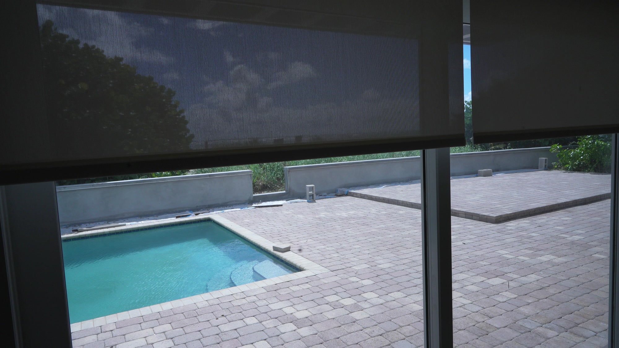 SheerWeave 4000 Eco solar screen lowering over the pool and sea grape view on a Somfy Sonesse 30 Zigbee motor