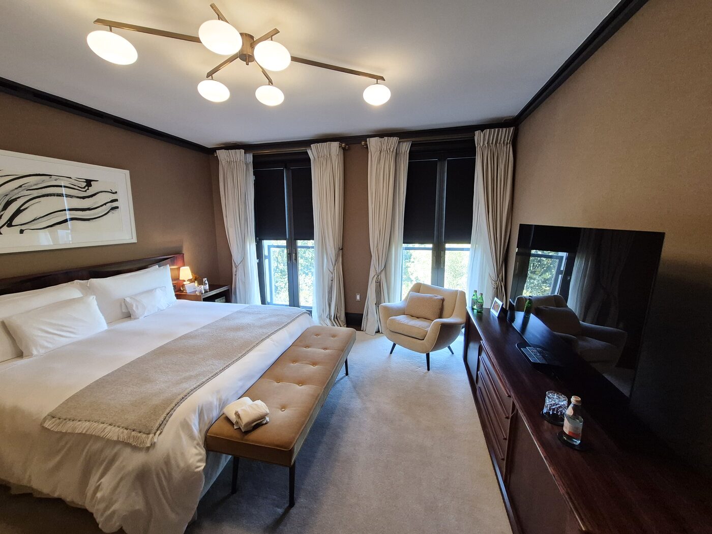 Bedroom with motorized blackout rollers lowered behind the chenille drapery