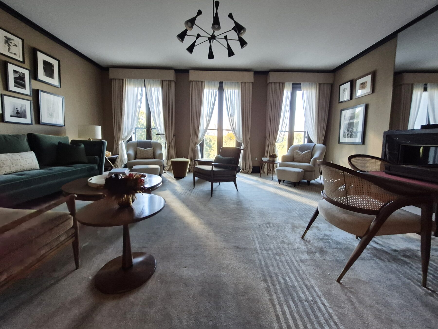 Living room with three French windows dressed in chenille drapery and striped sheers
