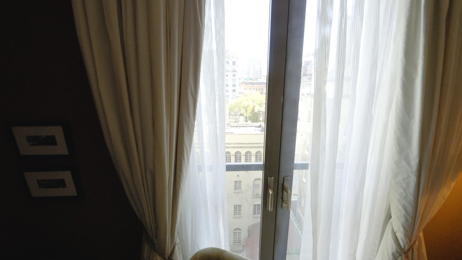 Striped white sheers drawn across the window wall with the city beyond