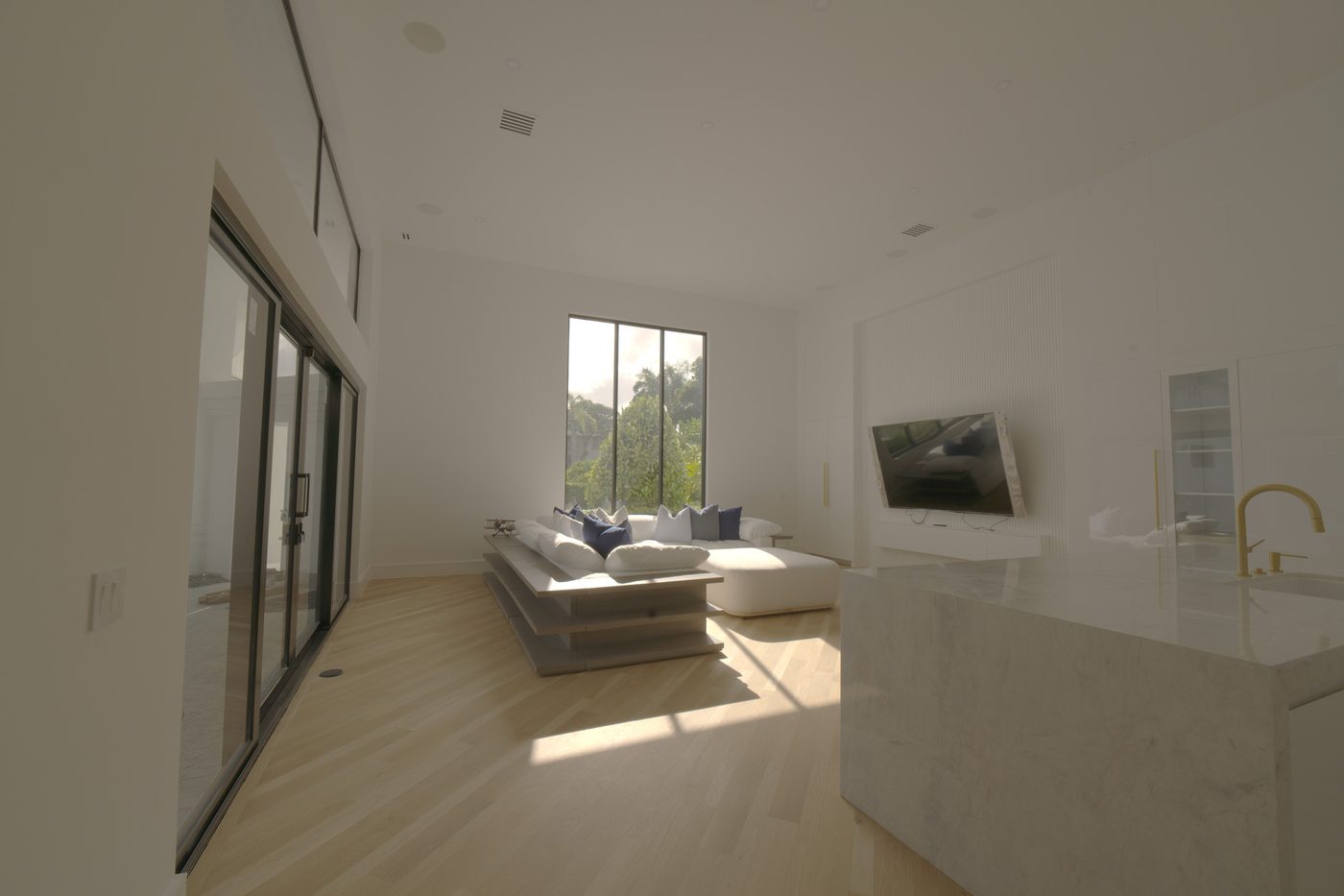 Guest house living room with a tall window, sofa and kitchen island