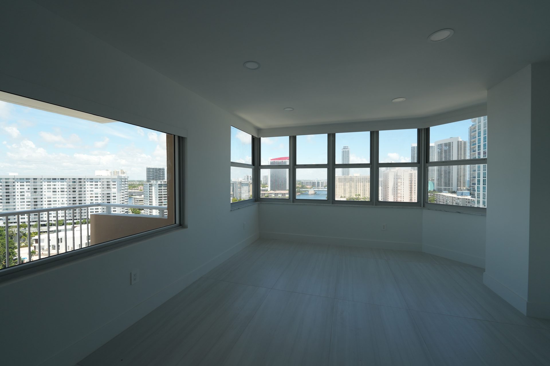 Living room with roller shades rolled up above every window, skyline and water in view, Hallandale Beach