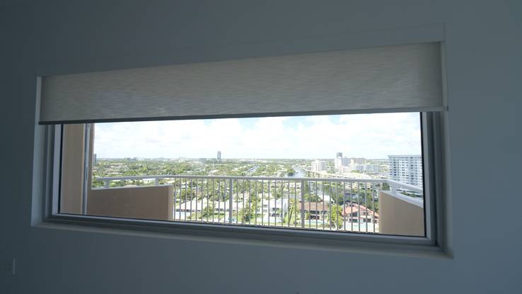 A wide window with the shade rising from behind the lacquered basswood valance, the neighbourhood and canal beyond