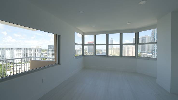 Living room at The Hemispheres with the Elba Daylight shades raised and the city and ocean in the wraparound windows
