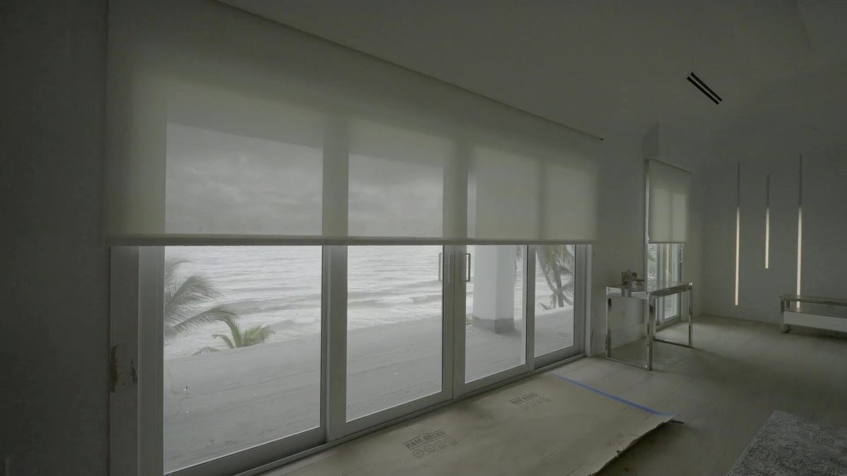 Solar screen of the dual shade rising to reveal the ocean in the Hillsboro Mile primary bedroom, on Lutron Sivoia QS motors