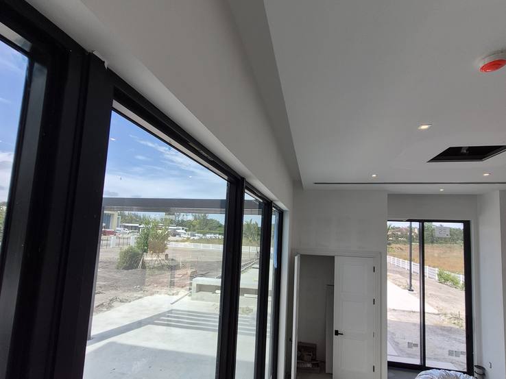 The empty ceiling pocket running above the sliding glass doors during construction
