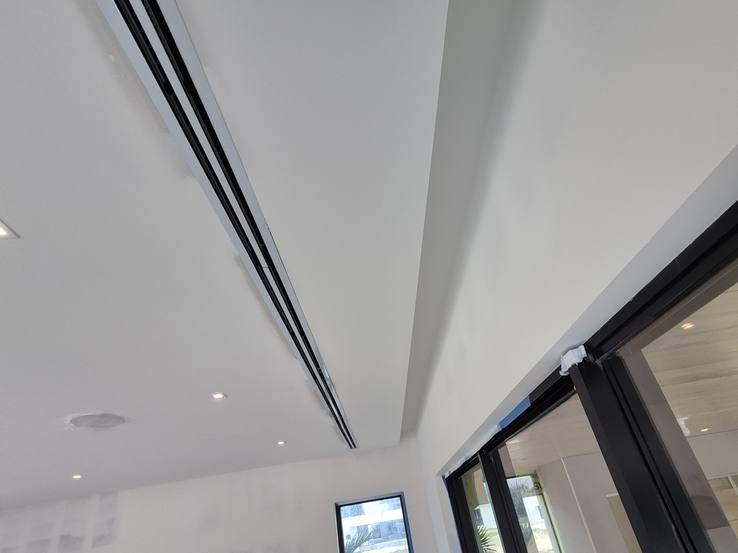 Empty ceiling pockets running along the top of a wall of glass during construction