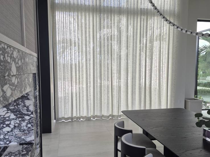 Dining room with the tall sheers beside the marble bar and the table