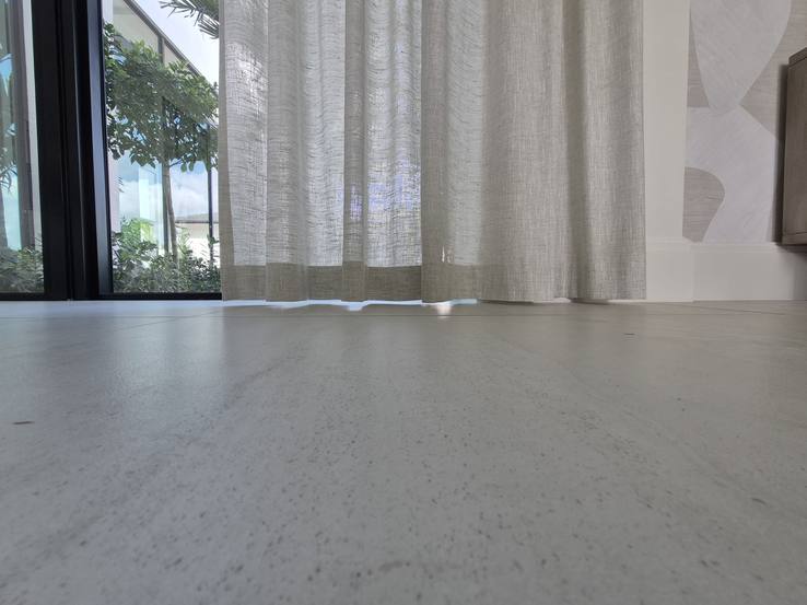 The hem of the tall sheer drapery finishing flush to the stone floor