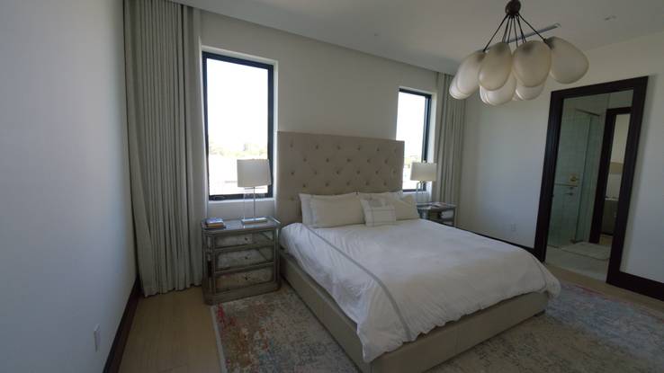 Bedroom with flat Roman shades and drapery on both windows, all from the ceiling