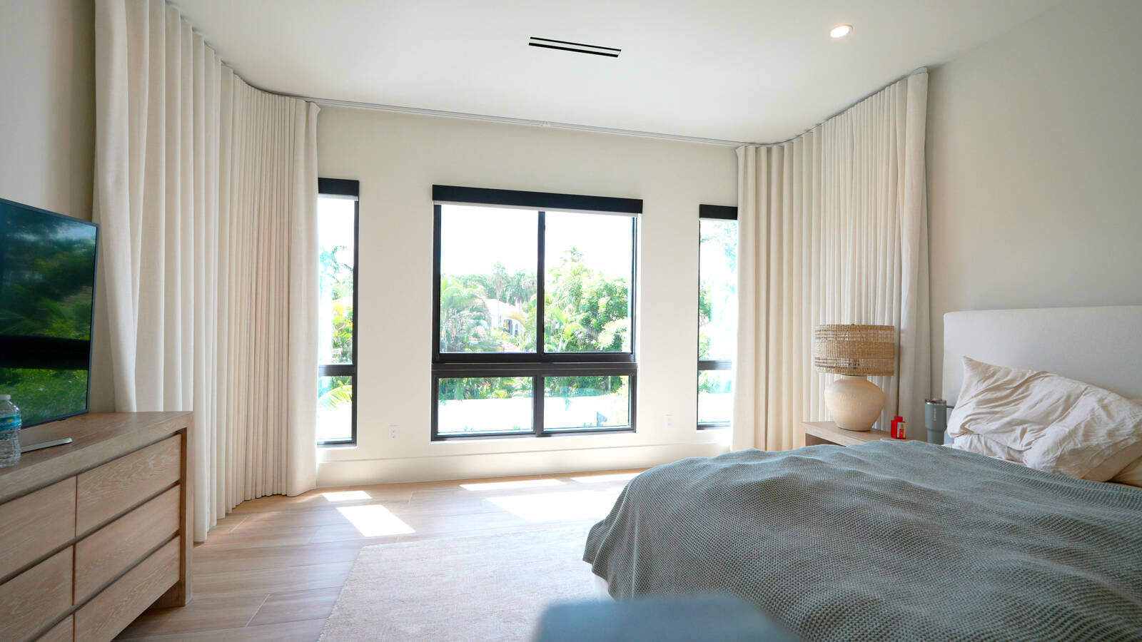 Boca Raton master bedroom bay with the blackout drapery open on a bent motorized track, the stack parked clear of the glass
