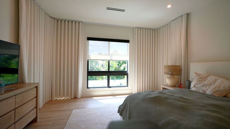 Blackout drapery closing around the bent track over the master bedroom's three angled windows