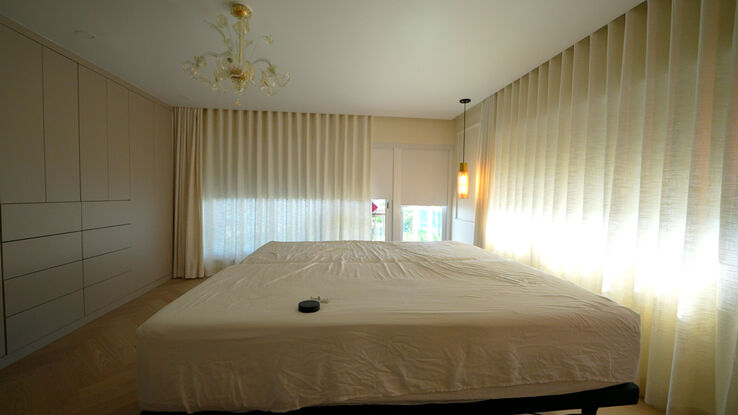 Master bedroom with the linen drapery drawn and the pendant lamp lit