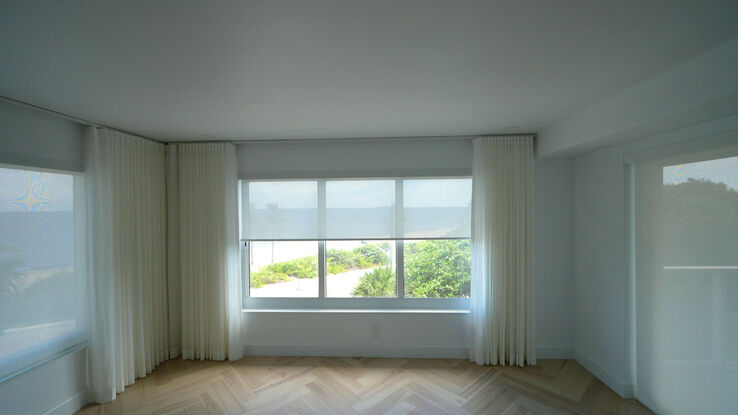 Window and door sharing a wall, with sheers on the recessed track and solar screens behind