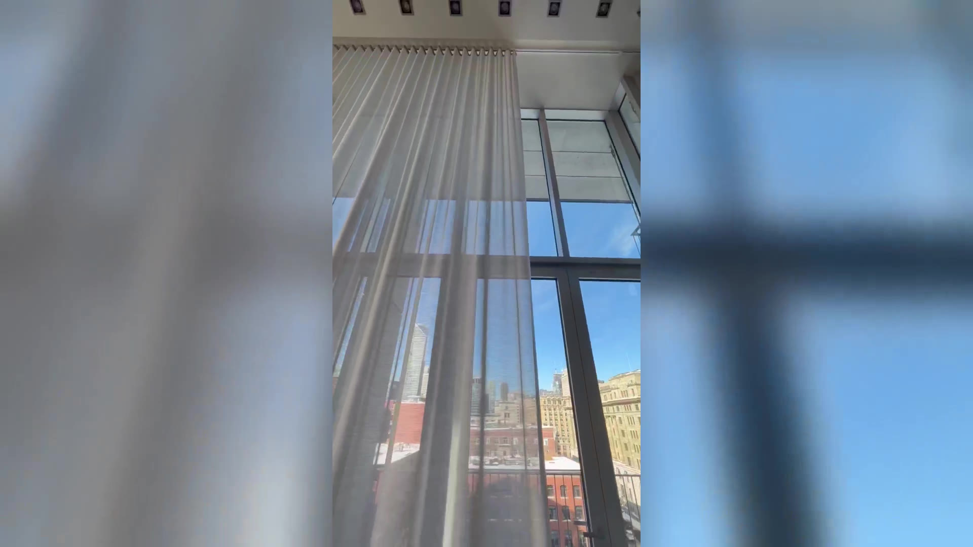 Sheer curtains drawn across the glass wall with the Old Port skyline beyond