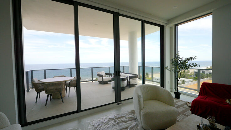 Living room open to the terrace and the ocean with the screens fully raised