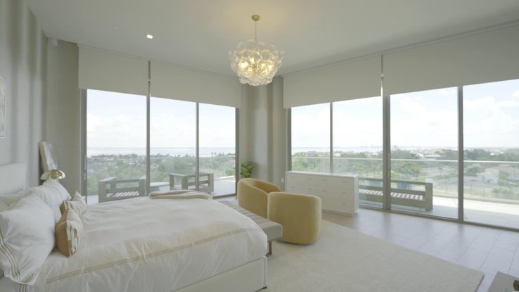 Primary bedroom with chandelier, motorized rollers and drapery at the St. Regis Longboat Key