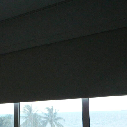 Berlin Snow White blackout roller shade in side channels, seen against the ocean light