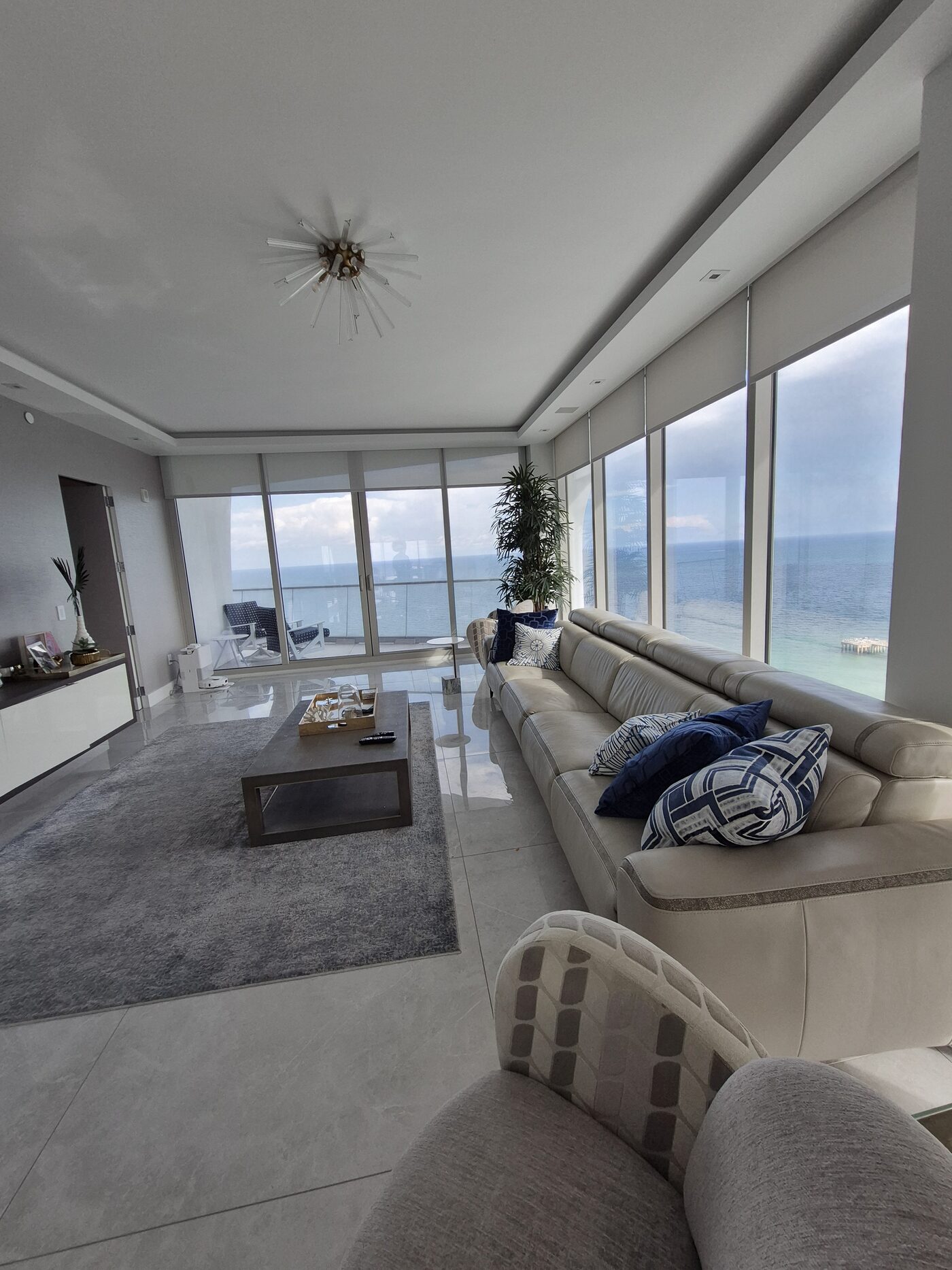 Great room with recessed Crestron solar shades along the oceanfront glass in Sunny Isles Beach