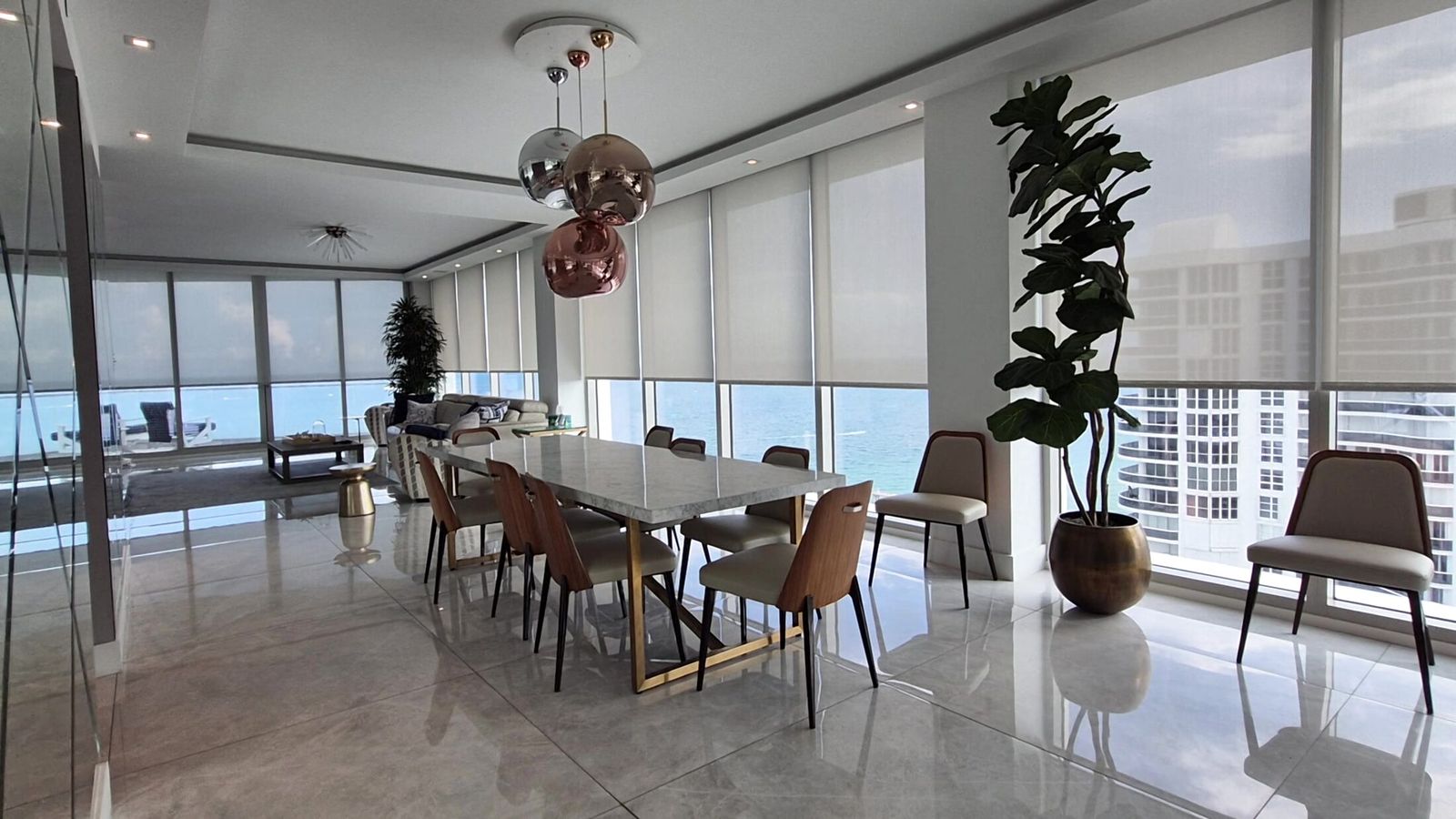 Recessed Crestron motorized roller shades in Mermet E Screen 5% White along the ocean wall of a Trump Tower III dining room