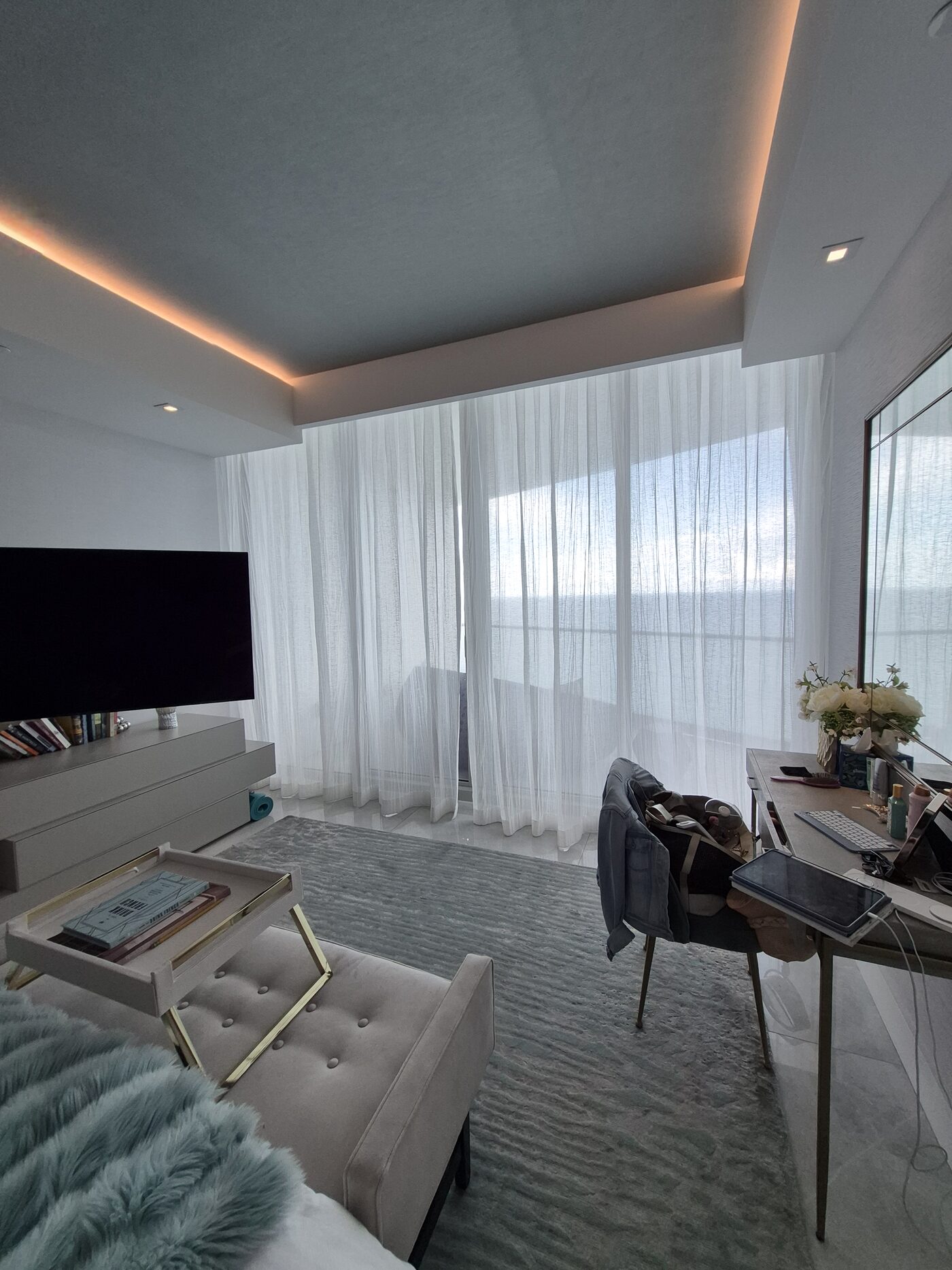 Fabricut sheer drawn across the primary suite window wall with the ocean behind it
