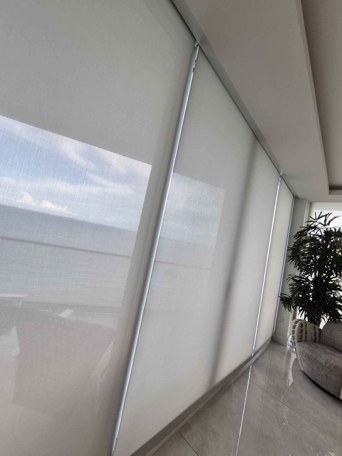 Recessed Crestron roller shade lowered against floor to ceiling glass in Sunny Isles Beach