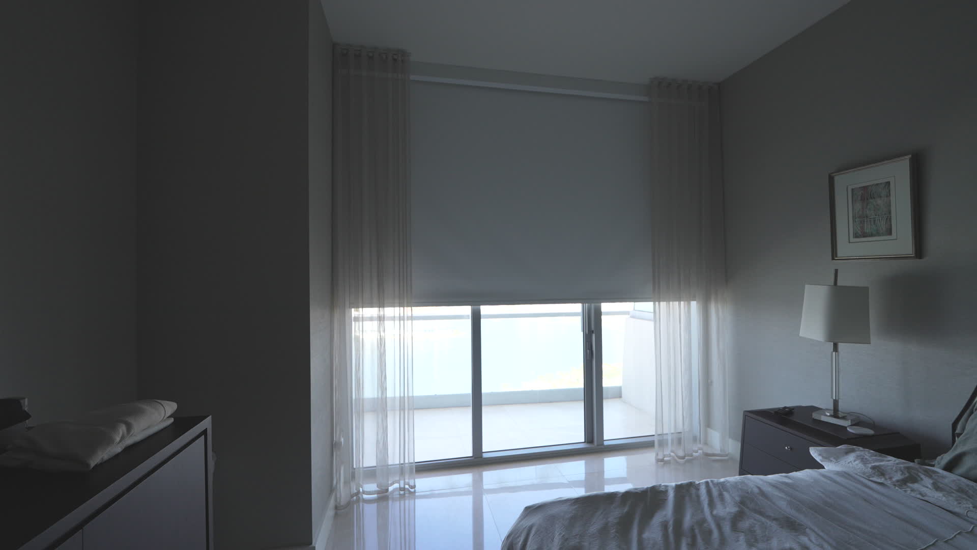 Bedroom blackout roller shade lowered in side channels with sheers at the corner glass