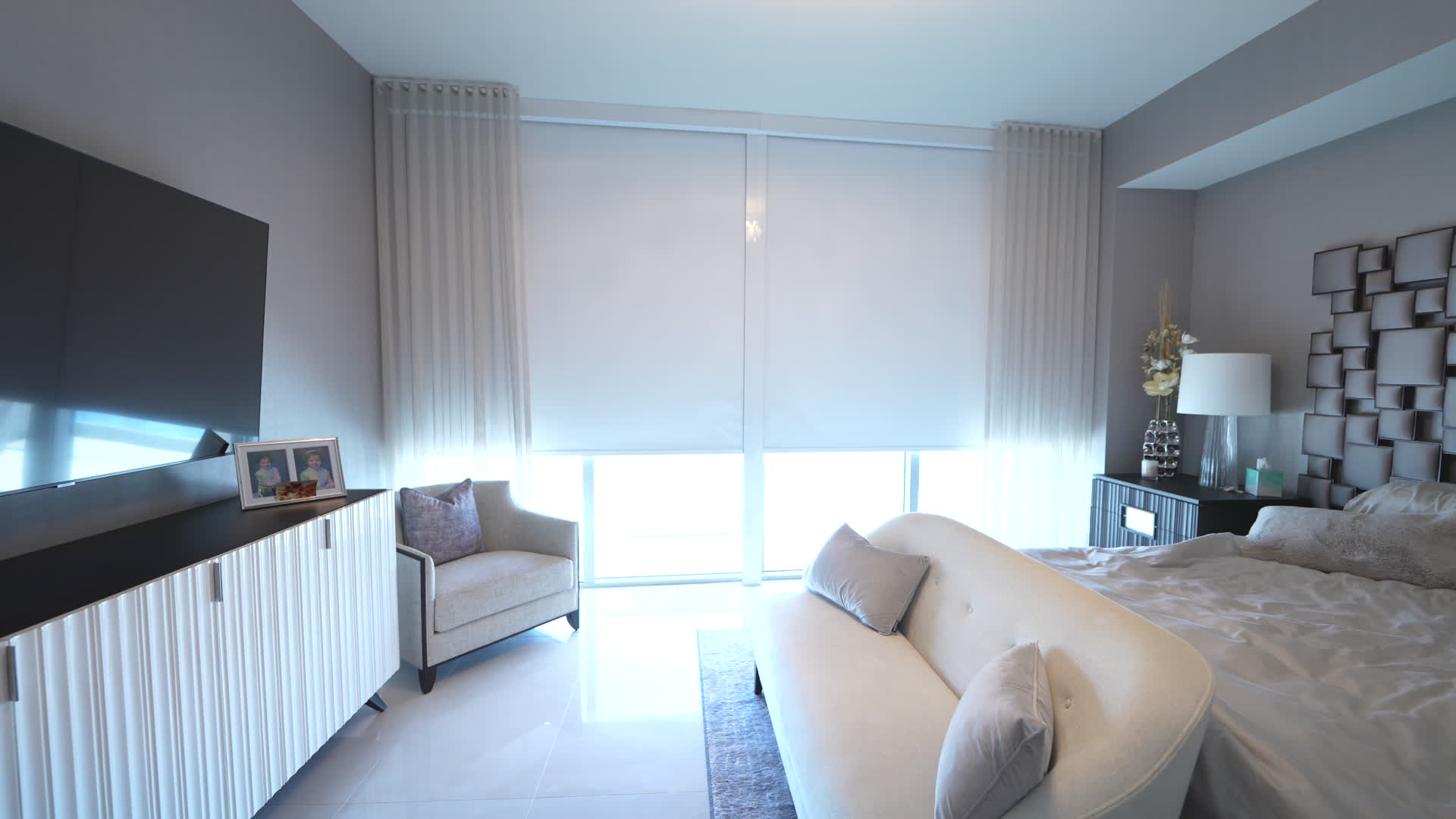Primary bedroom with motorized roller shades and Romo Zyla sheers over the ocean